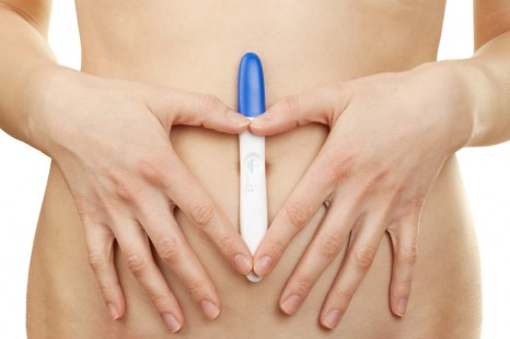 Woman holding a positive pregnancy test against white background