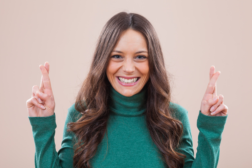 Portrait of happy woman with fingers crossed